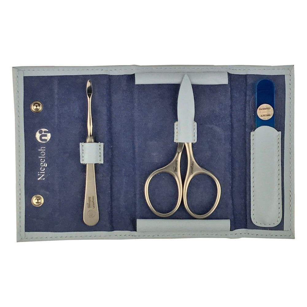 Coffret manucure bébé bleu. Ciseaux, lime à ongles et repousse-cuticules inclus. Étui bleu avec boutons dorés. Marque Niegeloh.