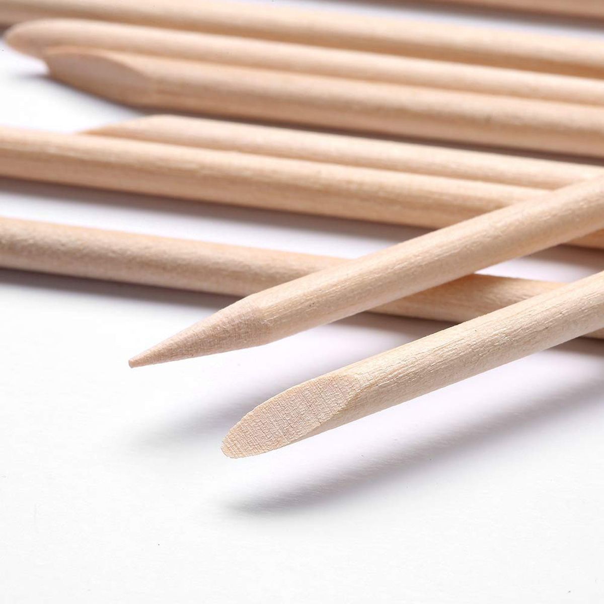 Gros plan sur des bâtonnets de manucure en bois de rose. Couleur bois, pointes pointues et arrondies. Plusieurs bâtonnets côte à côte.