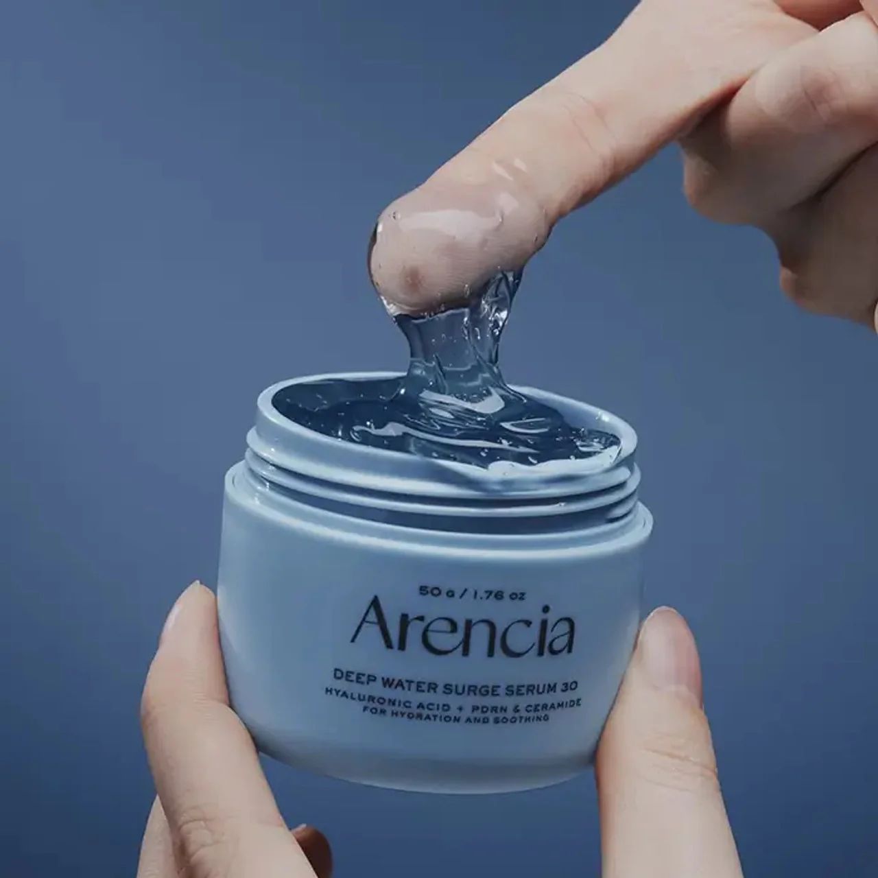Lichtblauwe pot met AENCIA DEEP WATER SURGE SERUM 30. Heldere geltextuur wordt met een vinger uitgenomen.