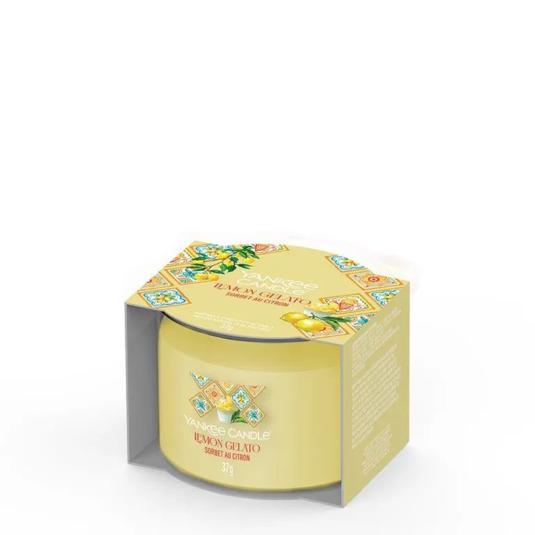 Bougie jaune dans son emballage. Inscription: Lemon Gelato. Emballage à motifs floraux. Bougie cylindrique.
