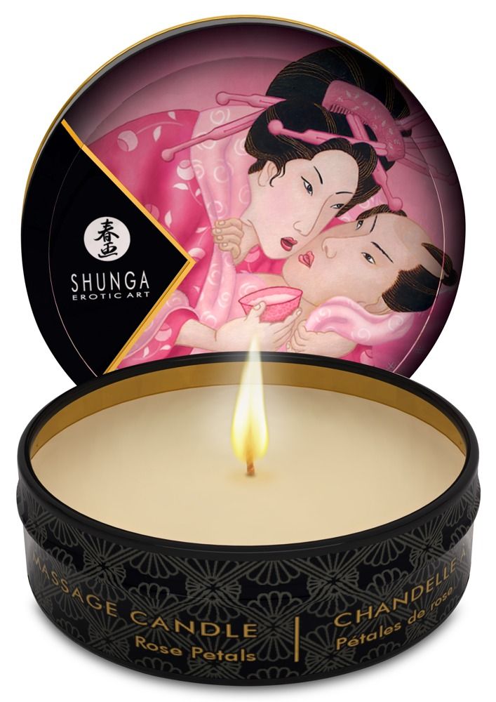 Ronde zwarte kaars met gouden rand. Geïllustreerde deksel. Vlam brandt. Tekst: Massage Candle, Rose Petals.