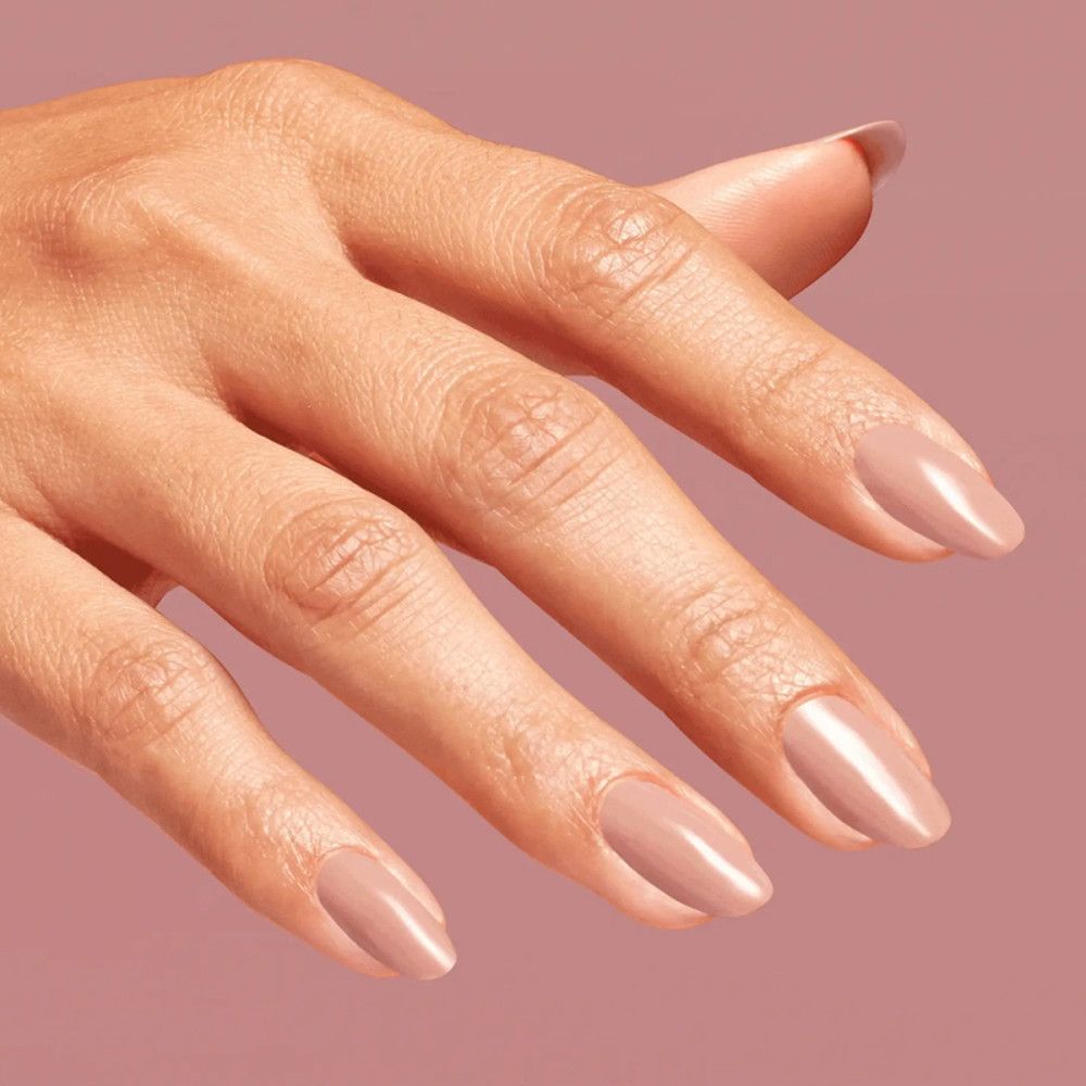 Main avec ongles vernis. Vernis à ongles rose clair. Finition brillante.