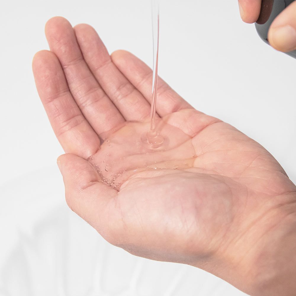 Shampoo wordt uit een dispenser in een handpalm gegoten.