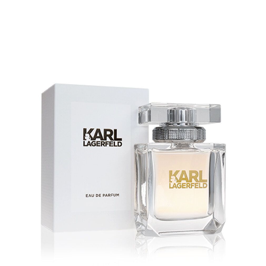Flacon de parfum et emballage. Flacon carré, transparent, avec bouchon argenté. Emballage blanc avec logo et informations produit.