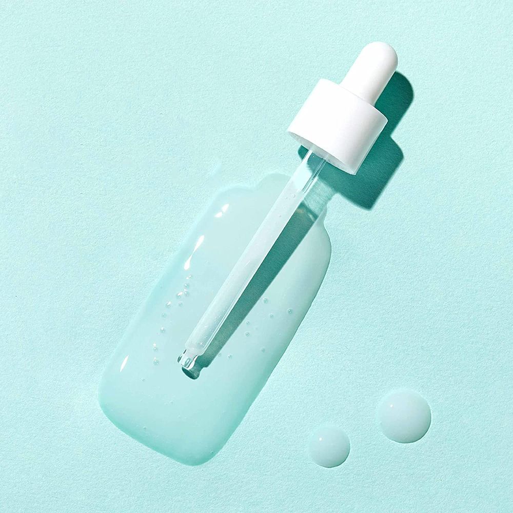 Liquide transparent avec pipette sur fond bleu clair. Deux gouttes à côté.