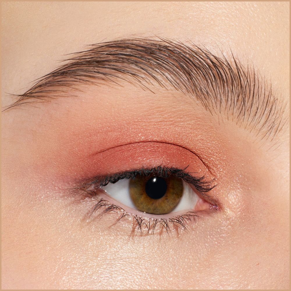 Gros plan sur un œil avec fard à paupières rose. Sourcil et cils clairement visibles.