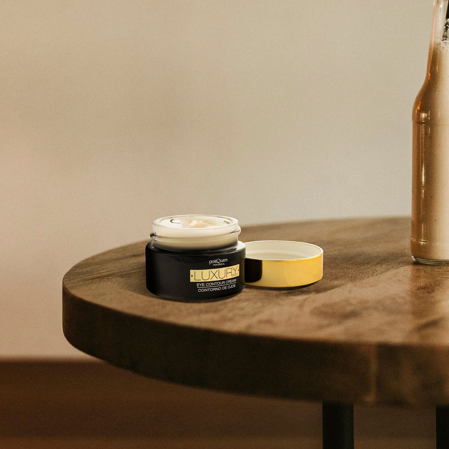 Pot ouvert sur une table. Couvercle doré à côté. Nom du produit: LUXURY GOLD EYE CONTOUR CREAM.