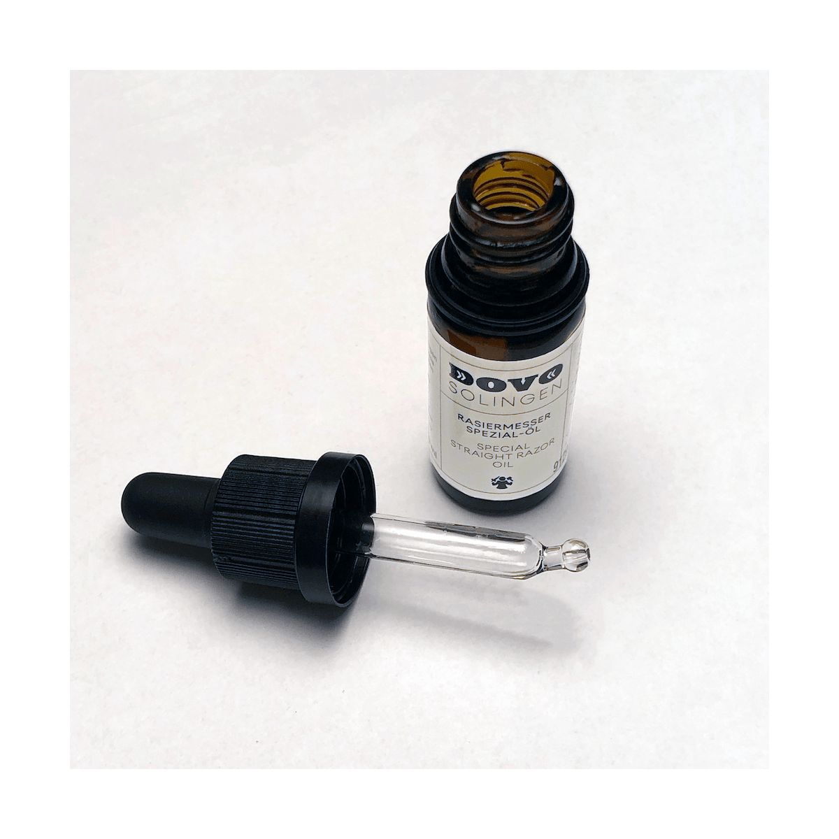 Flacon en verre brun avec bouchon noir et pipette. Étiquette avec texte DOVO Solingen. Huile spéciale pour rasoir.
