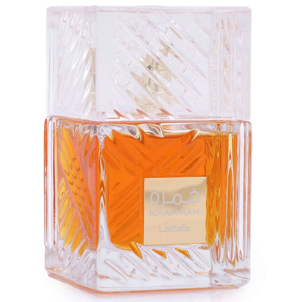 Flacon de parfum carré en verre transparent texturé. Liquide doré visible. Étiquette dorée avec inscription.