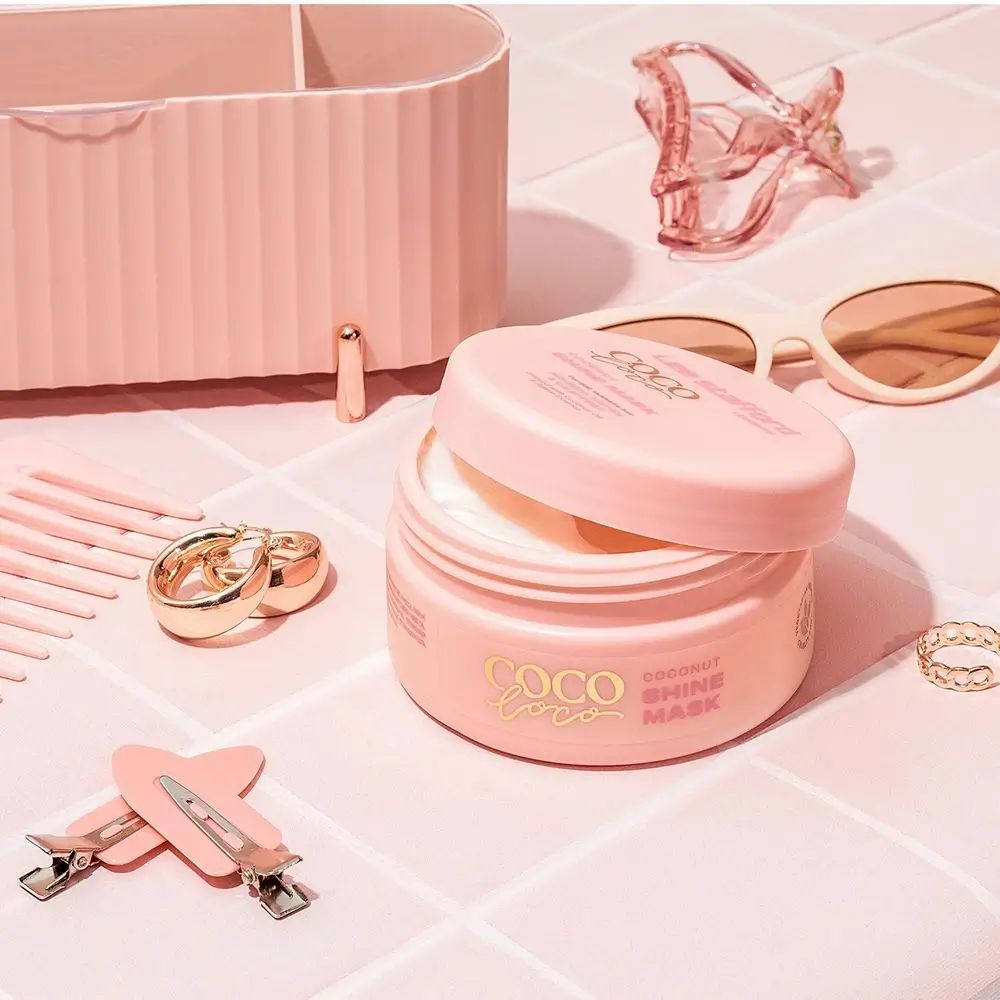 Open pot Coco Loco, Coconut Shine Mask, omringd door accessoires: haarclips, sieraden, zonnebril.