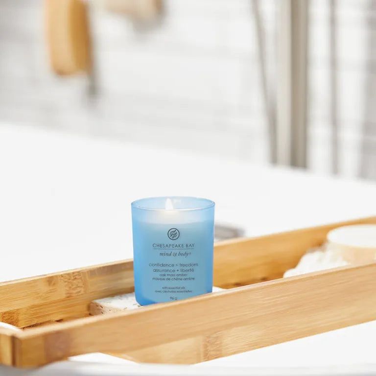 Bougie bleue Chesapeake Bay, Confiance + liberté, sur un plateau en bois dans une salle de bain. Inscription Mind & Body.