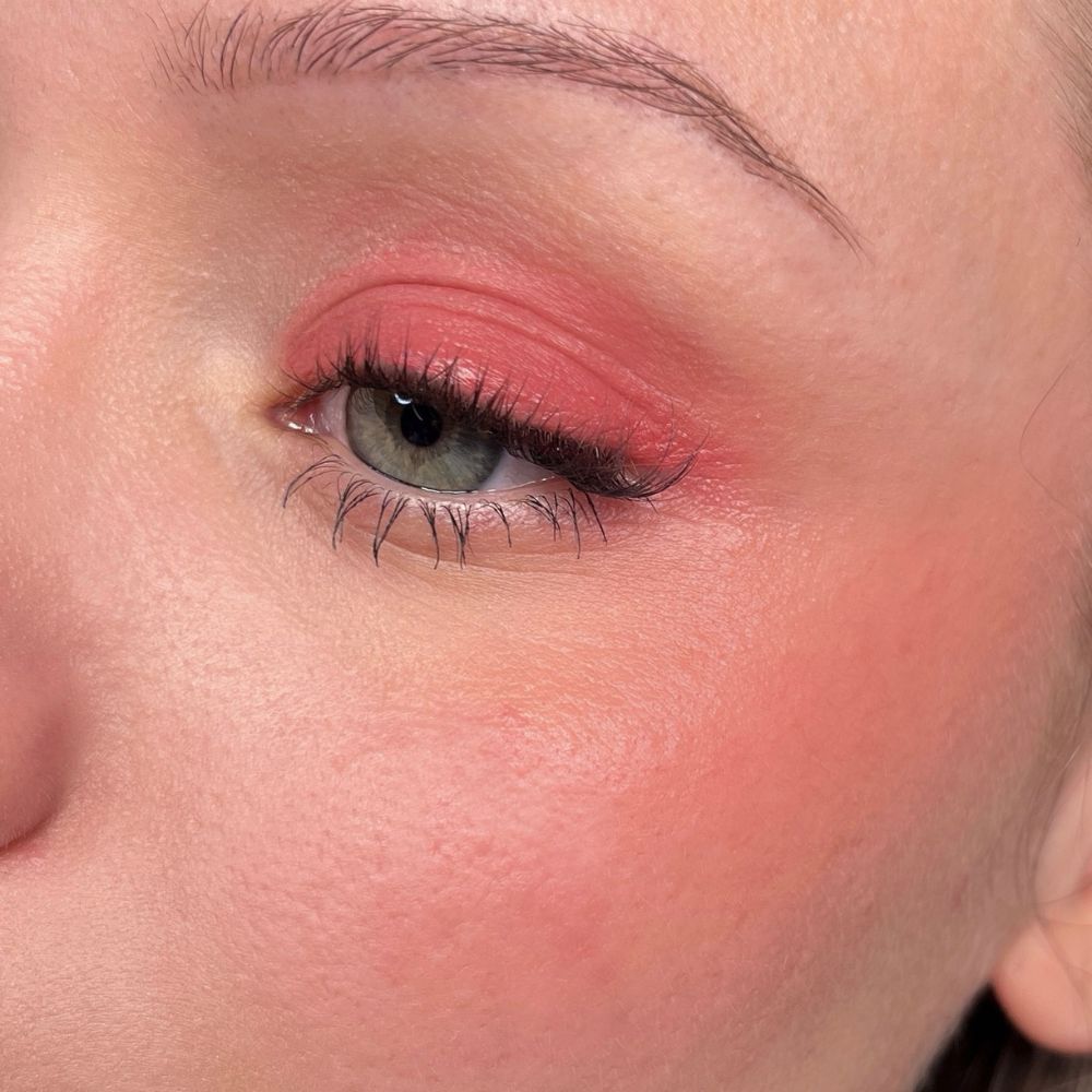 Close-up van een oog met roze oogschaduw en blush. Groene ogen.