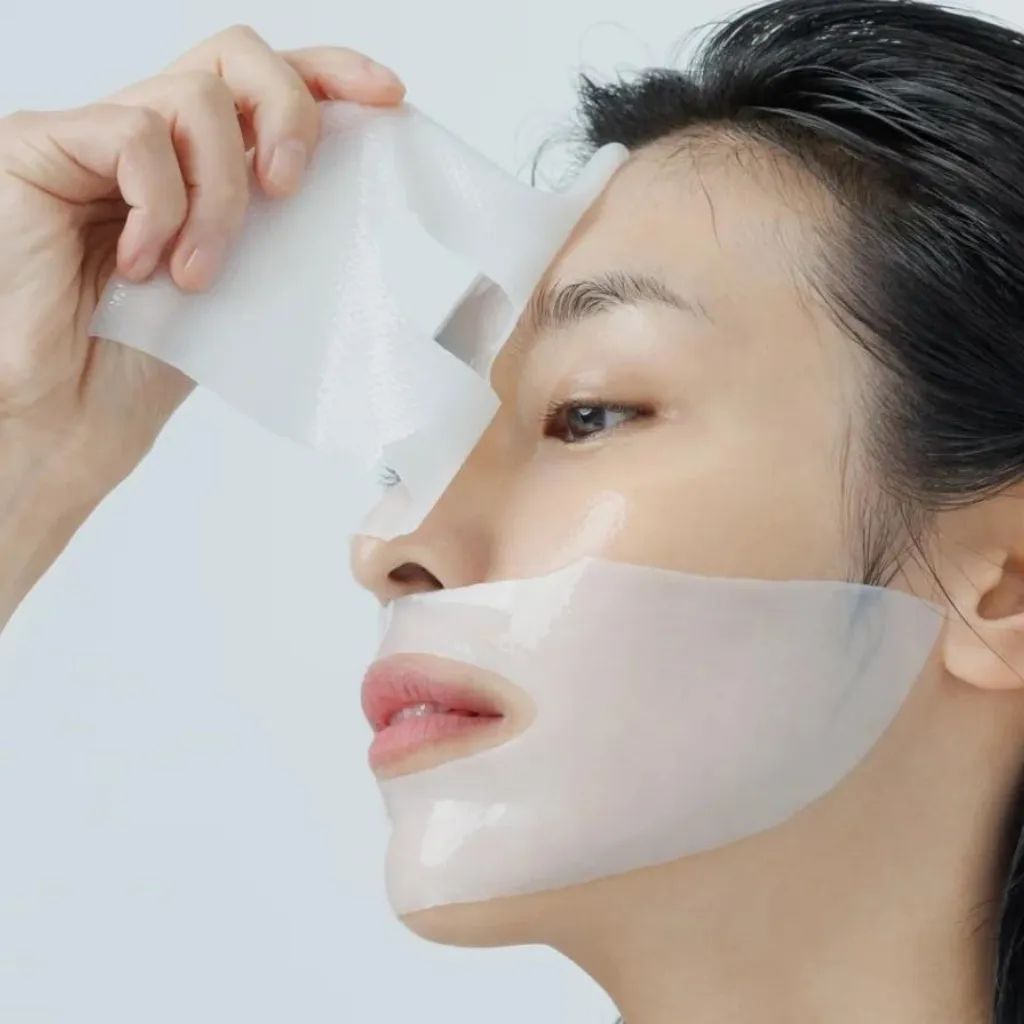 Vrouw met gezichtsmasker. Het masker wordt van het gezicht getrokken. Het gezicht is gedeeltelijk bedekt.