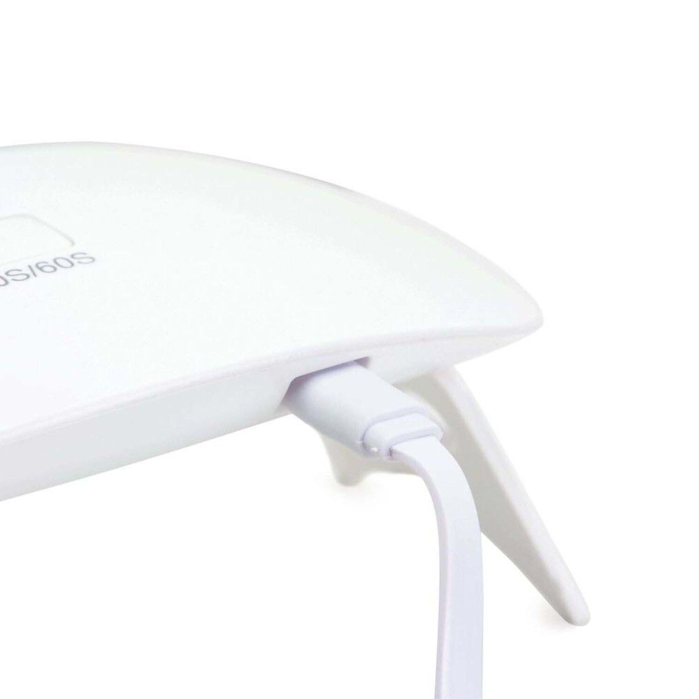 Gros plan d'un câble USB blanc branché sur une lampe LED blanche.