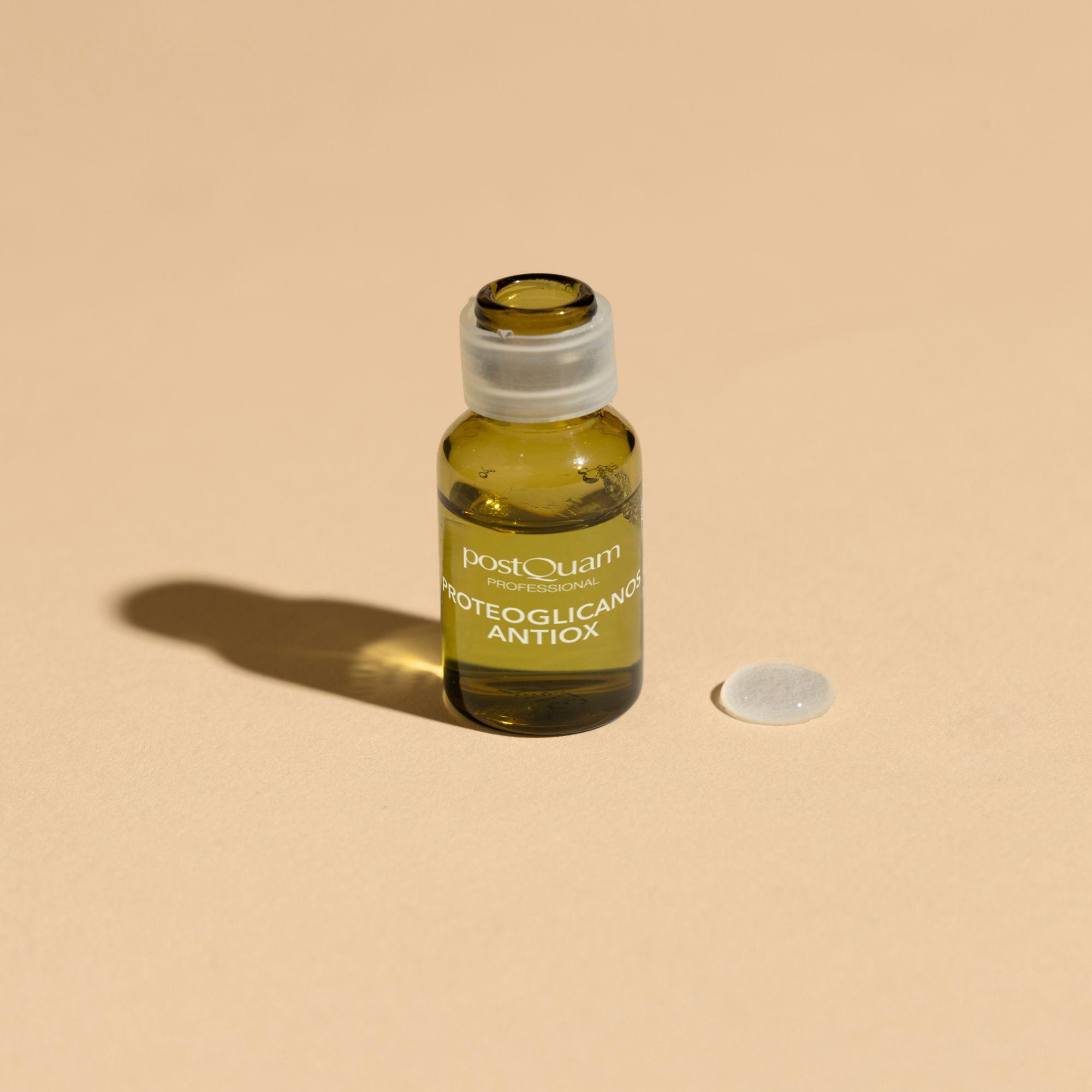Une seule ampoule Postquam Proteoglykane Antioxidant avec bouchon et un bouchon à côté. Sur fond clair.