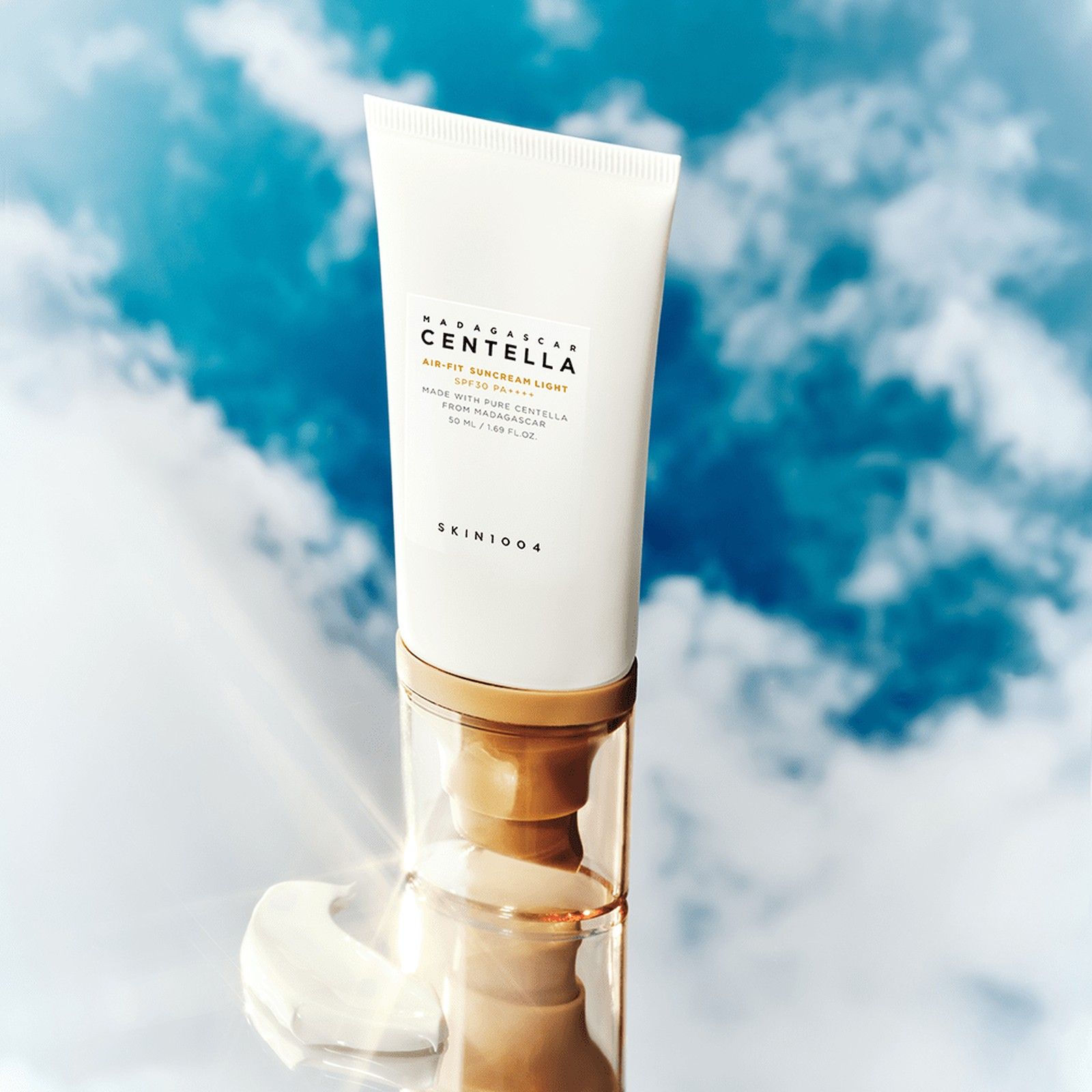 Tube SKIN1004 Air-Fit Suncream Light SPF30 sur un miroir devant un fond de ciel.