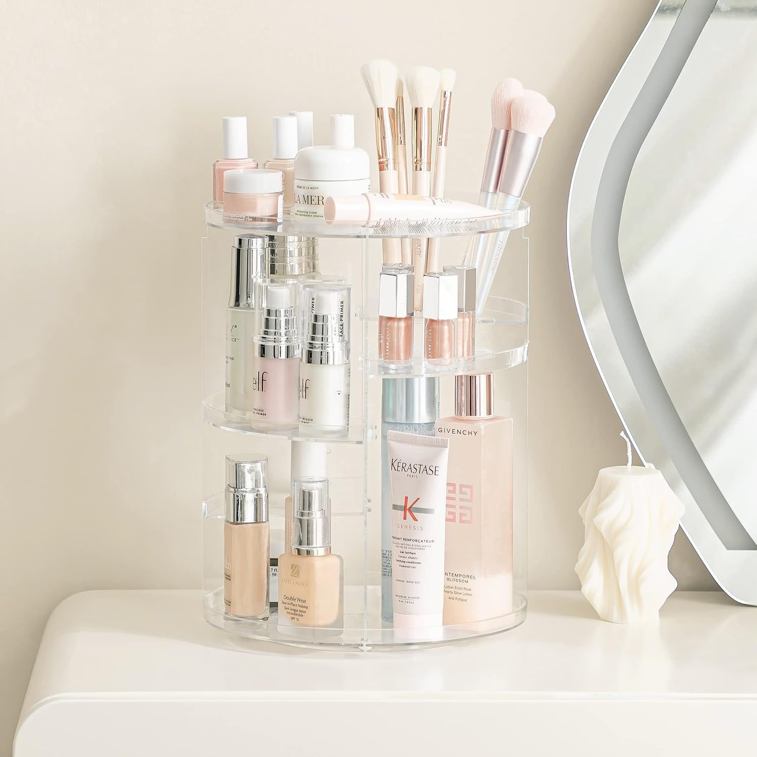 Organisateur cosmétique rotatif en acrylique transparent à plusieurs niveaux, rempli de produits de beauté et de pinceaux.