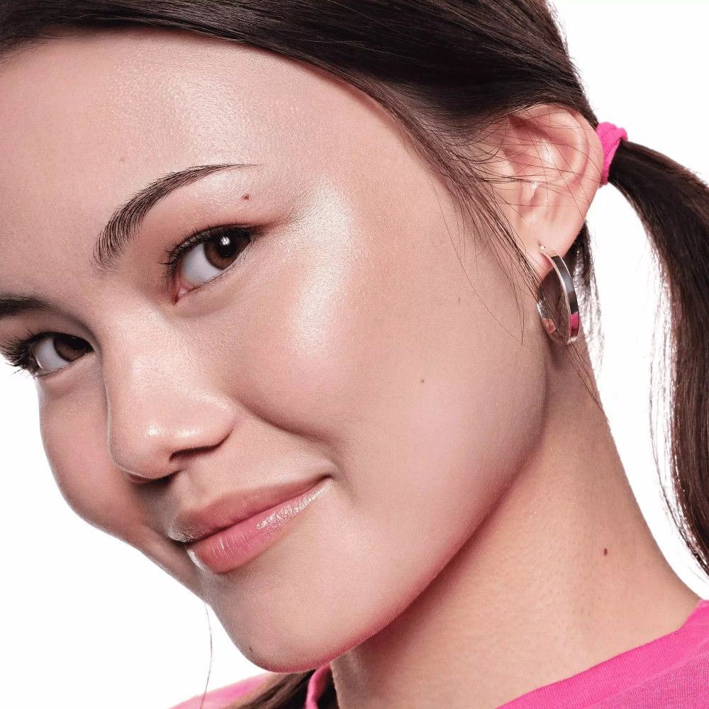 Close-up van een vrouw met gehighlighte huid. Ze draagt een roze top.