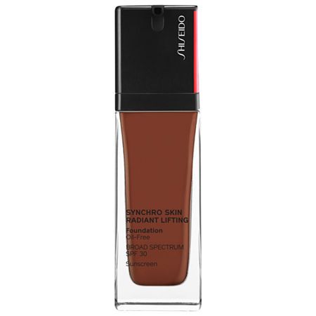 Flacon de fond de teint brun. Bouchon noir avec accent rouge. Inscription: Synchro Skin Radiant Lifting Foundation, SPF 30.