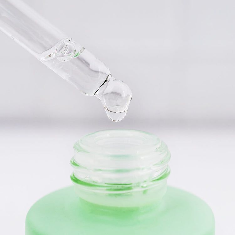 Une pipette avec une goutte de sérum au-dessus de l'ouverture d'un flacon âme pure Retinol & Vitamine C.