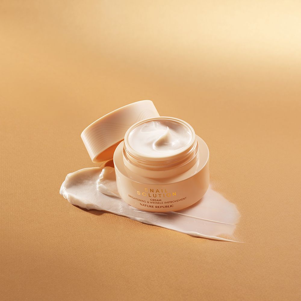 Beige crèmepotje met open deksel en crème-uitstrijk. Opschrift: NATURE REPUBLIC. Crèmetextuur zichtbaar.