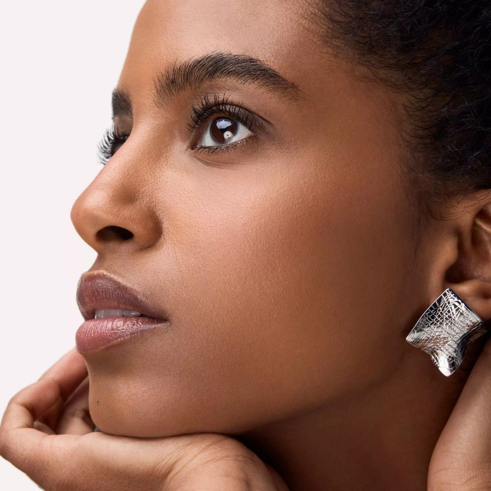 Portrait d'une femme avec de longs cils. Elle porte des boucles d'oreilles.