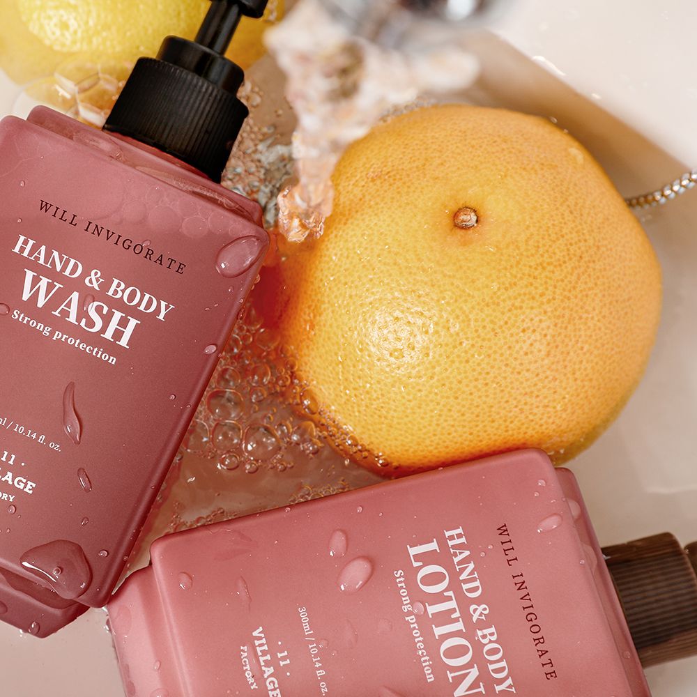 Deux lotions roses pour les mains et le corps et un flacon de lavage des mains avec pompe. À côté, un pamplemousse.