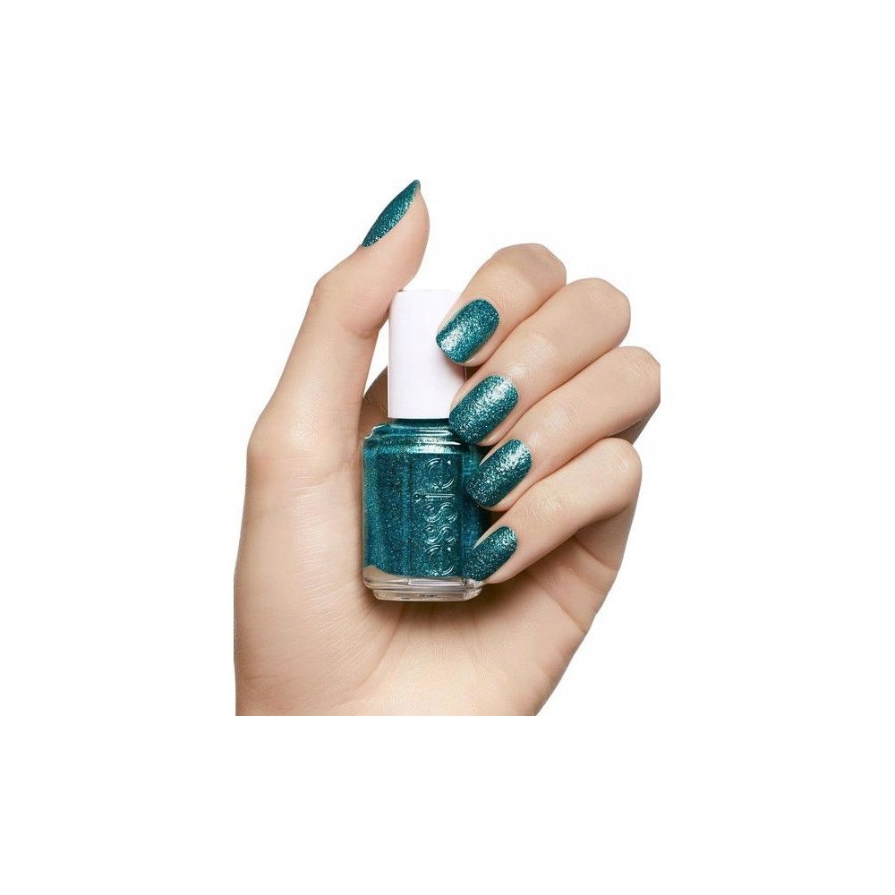 Hand houdt een flesje Essie nagellak vast. De lak is turquoise met glitter. De nagels zijn gelakt met dezelfde lak.