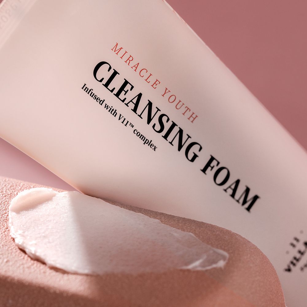 Close-up van een tube. Opschrift: MIRACLE YOUTH CLEANSING FOAM. Crème aangebracht op de huid.