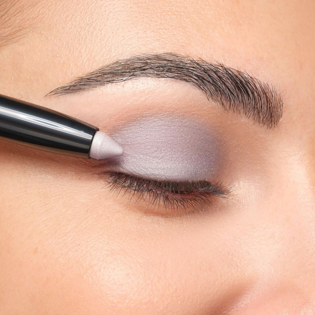 Oog met aangebrachte oogschaduw. Een Artdeco High Performance Eyeshadow Stylo wordt gebruikt. Wenkbrauw zichtbaar.