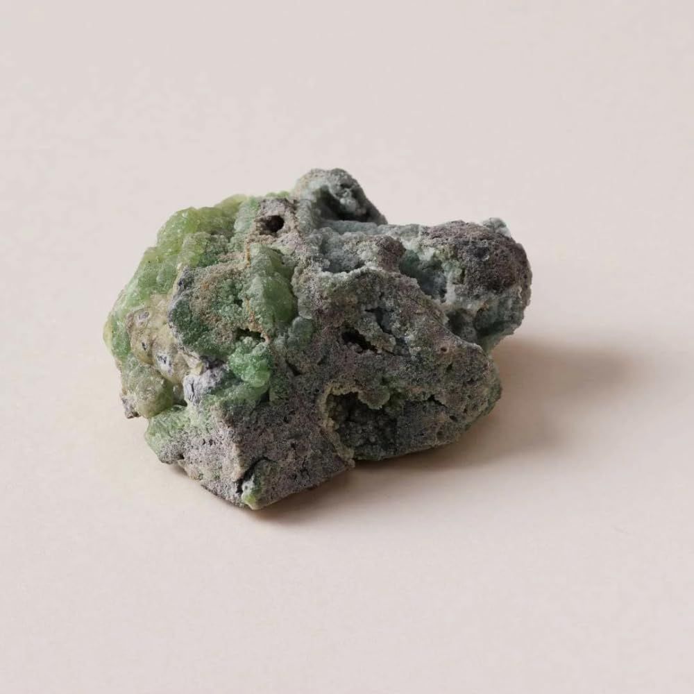 Groene steen met onregelmatige vorm en oppervlak. Grijze en groene tinten.