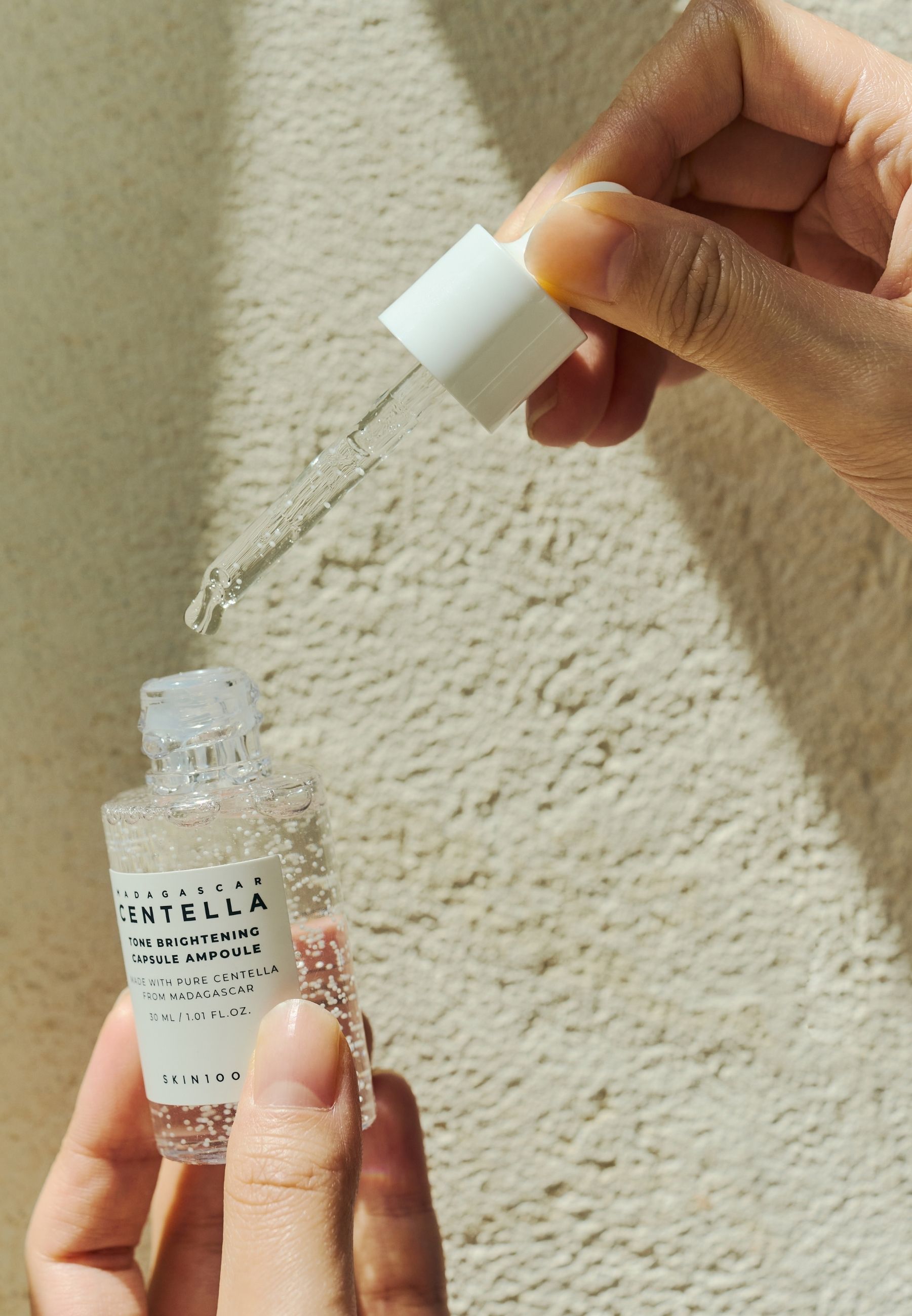 Handen houden een serumfles en pipet vast. Serum wordt uit de pipet gehaald.