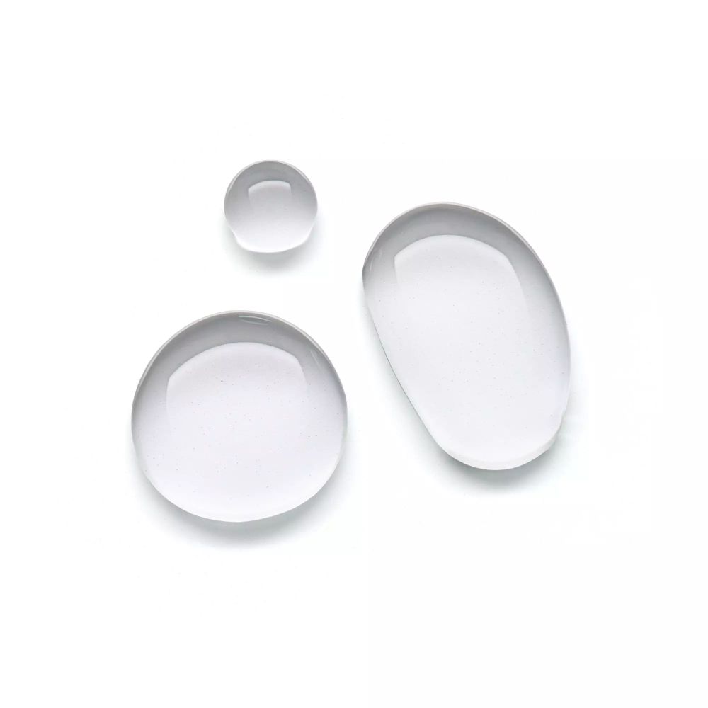 Trois gouttes de liquide transparentes sur fond blanc.