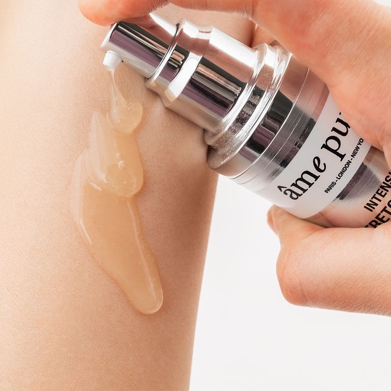 Een hand drukt op de pompdosering van een âme pure Intensive Stretch Mark Induction Therapy Gel, gel wordt op de huid aangebracht.