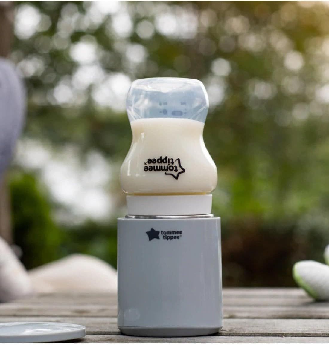 Grijze flessenwarmer met Tommee Tippee logo, met daarop een babyfles met blauwe dop.