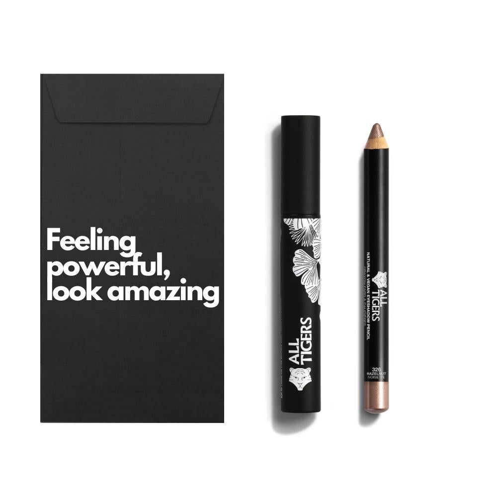 Zwarte verpakking met tekst. Mascara en potlood ernaast. Mascara met wit patroon en logo. Potlood met gouden punt.