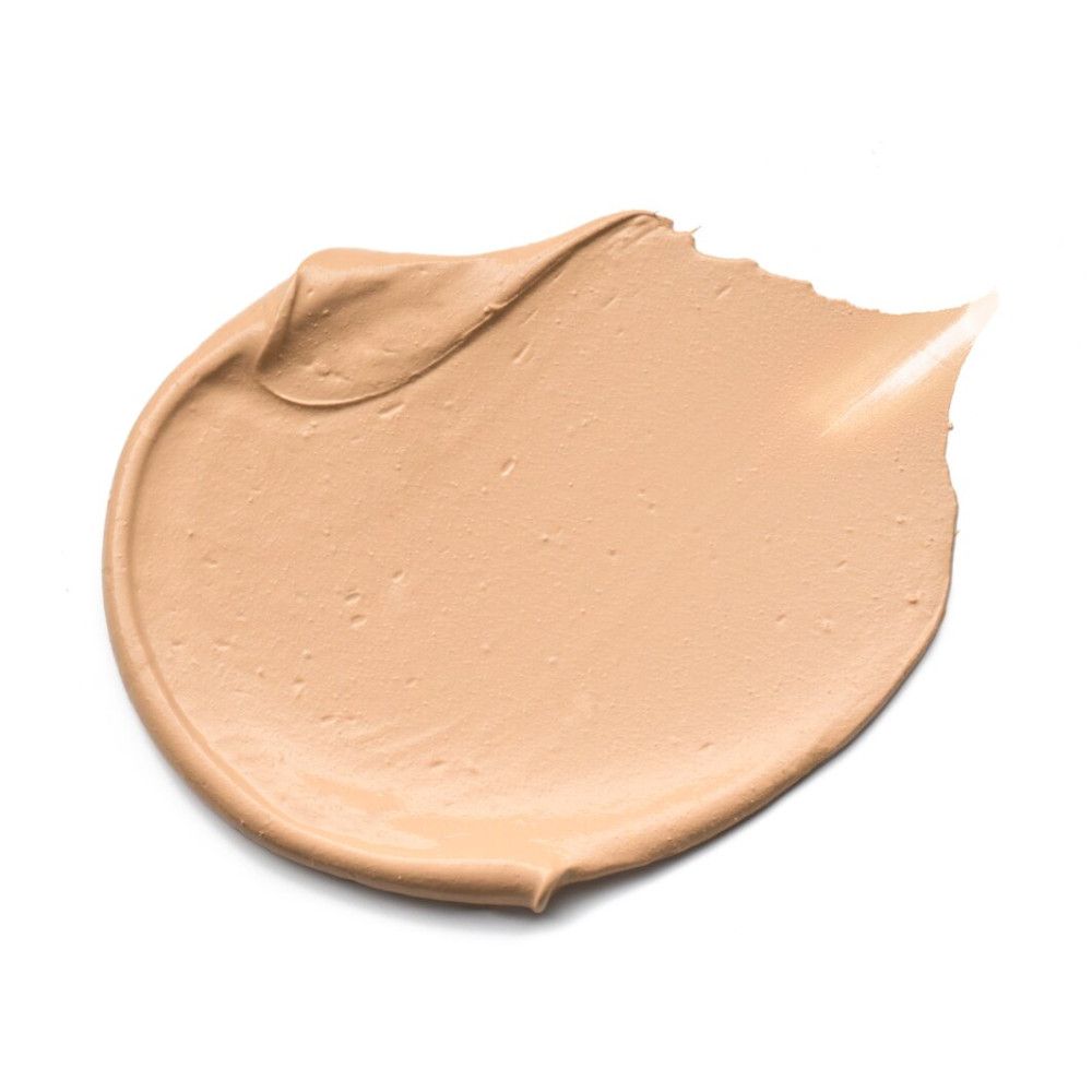 Vlek foundation, lichte tint, op witte achtergrond. Romige textuur, golfvormig.