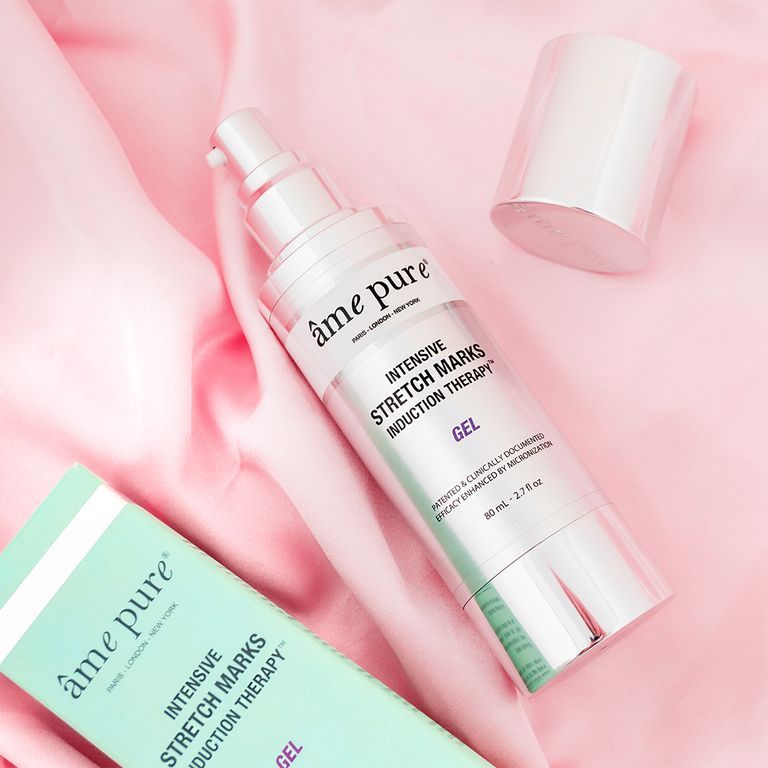 Een fles âme pure Intensive Stretch Mark Induction Therapy Gel en een tube liggen op roze zijde.