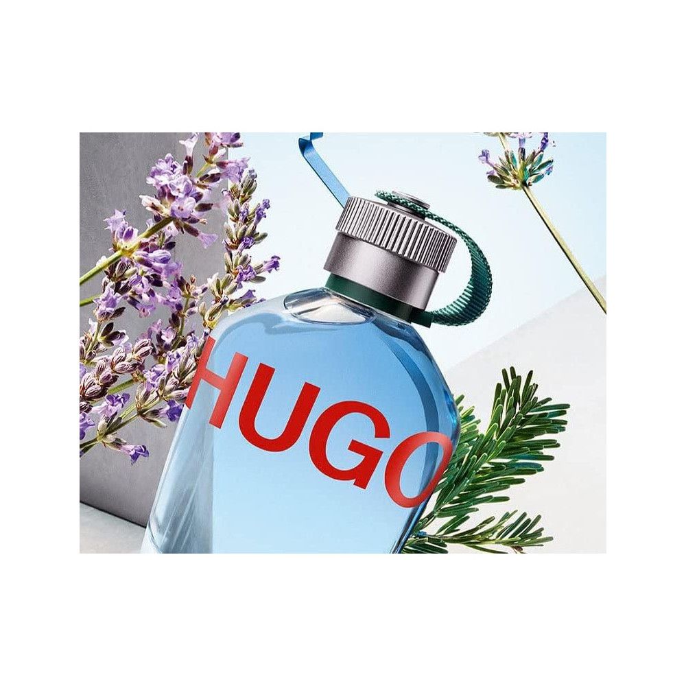 Flacon de parfum Hugo Boss bleu clair avec lettrage rouge HUGO. Bouchon argenté, boucle verte. Lavande et branches vertes.