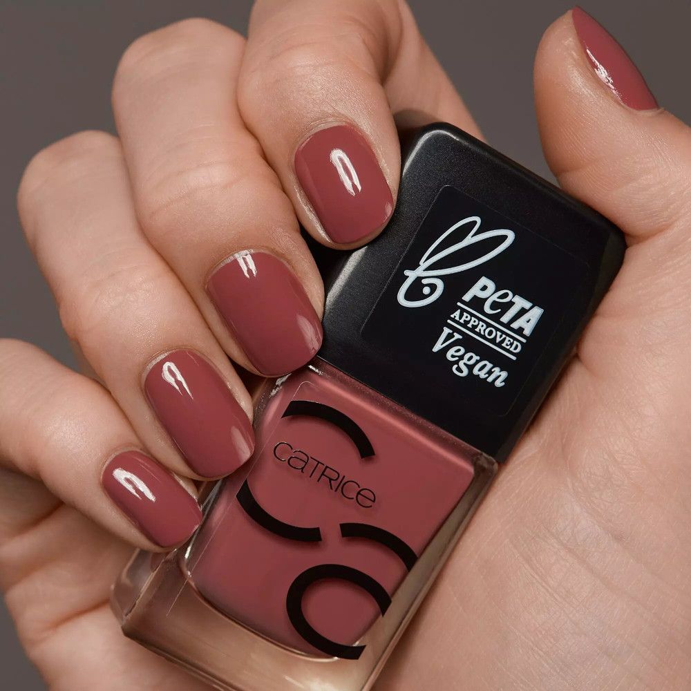 Main avec ongles vernis et flacon de vernis. Teinte rose. Marque Catrice, logo PETA.