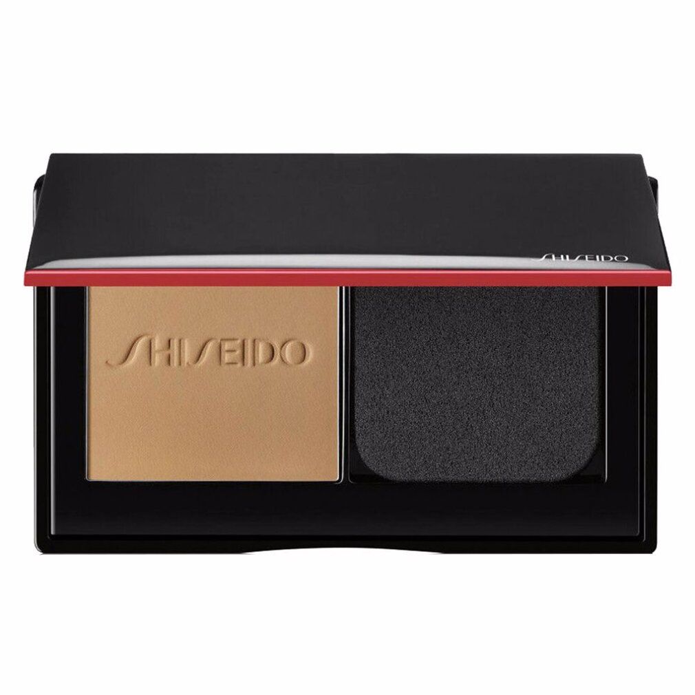 Poudre compacte ouverte avec poudre et éponge. Cadre noir, accent rouge. Logo Shiseido.