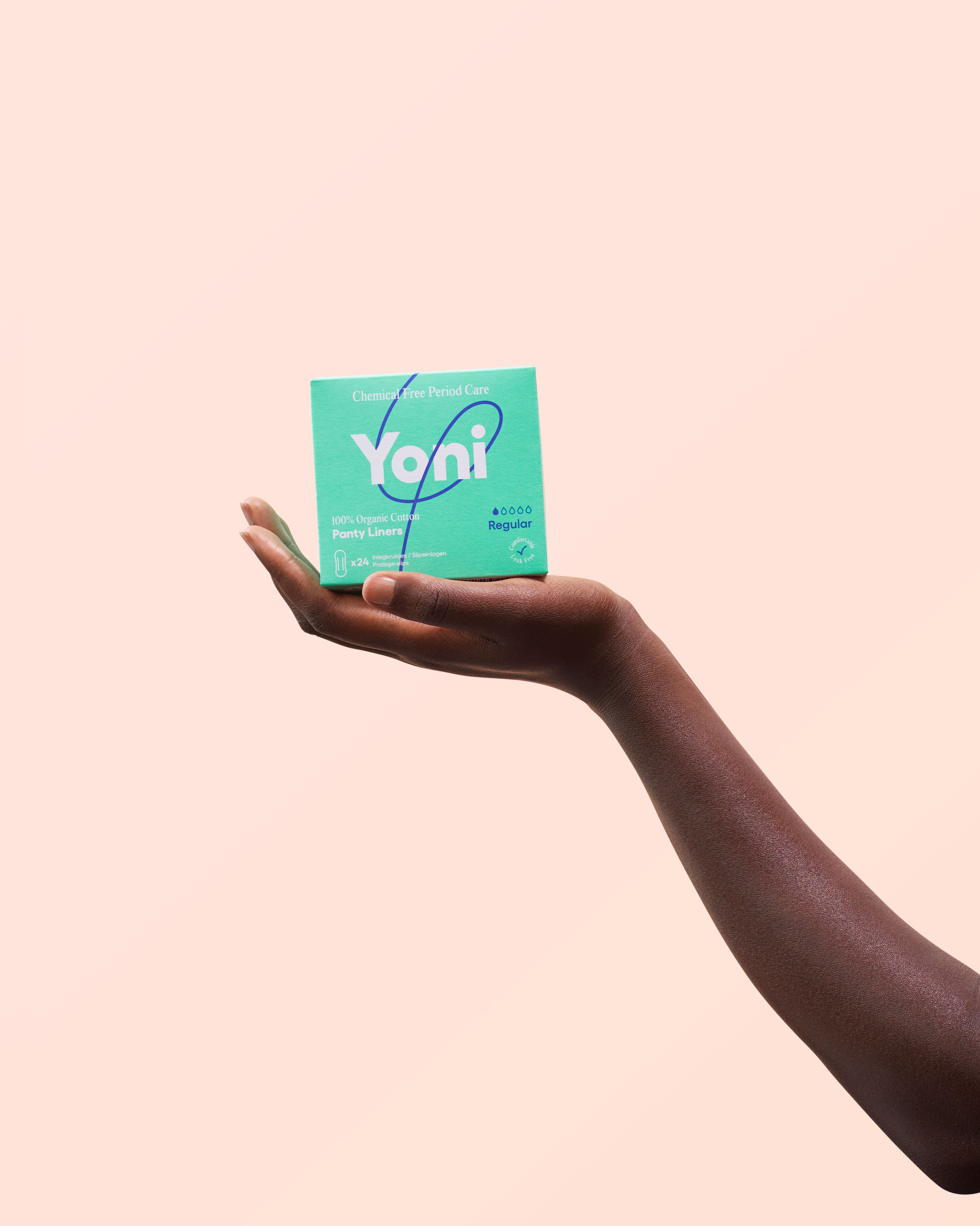 Main tenant une boîte verte Yoni. Inscription : Chemical Free Period Care, Regular, 100% Organic Cotton Panty Liners.