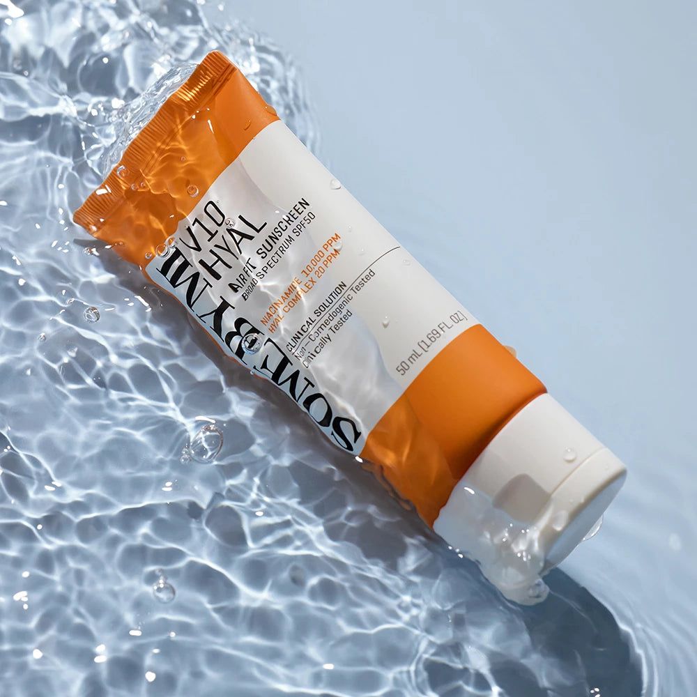 Tube de crème solaire dans l'eau. Tube orange et blanc avec texte : SOME BY MI V10 Hyal Air Fit Sunscreen SPF50.