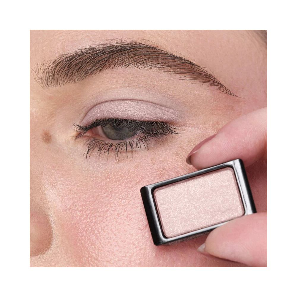 Œil avec fard à paupières appliqué. Personne tenant un contenant de fard à paupières.