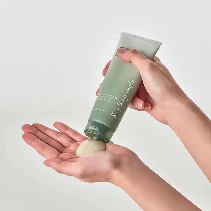 Handen houden groene tube vast. Product wordt op handpalm gedrukt. Opschrift: ANUA, HEARTLEAF LHA MOISTURE PEELING GEL.