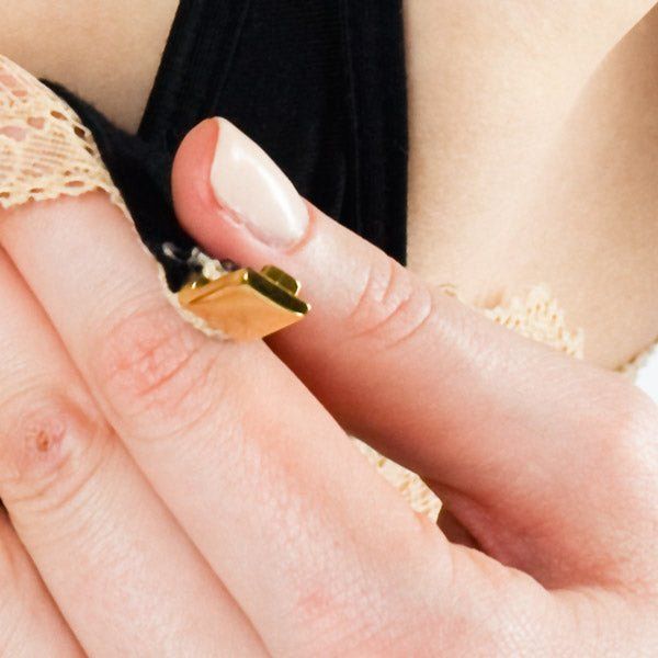 Close-up van de gouden sluiting van een BH. Vingers houden de sluiting vast.