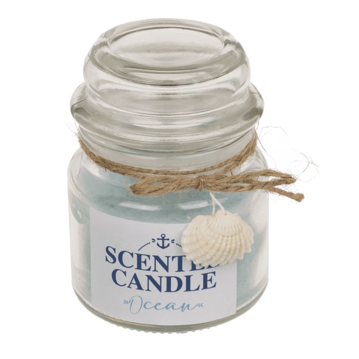 Bougie parfumée en verre avec couvercle. Cire bleue, étiquette avec ancre et texte "SCENTED CANDLE Ocean". Décorée d'un coquillage.
