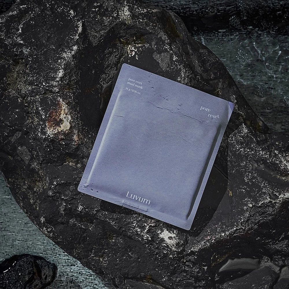 Emballage du masque facial sur une pierre sombre. Texte: Pore Reset Mud Mask, LUVUM.