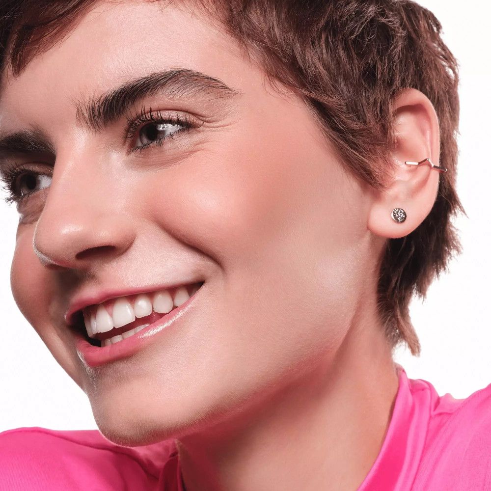 Gros plan d'un visage avec une peau bronzée. La personne sourit.