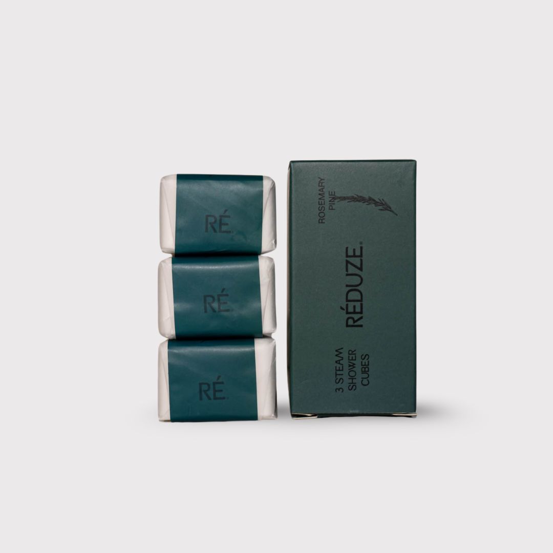 Drie doucheblokjes verpakt in groen papier, naast een groene doos met het RÉDUZE-logo.